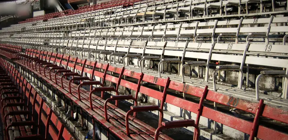Rows of empty red and white seats in the stands of the Estadio Monumental, Buenos Aires, on a raking diagonal.