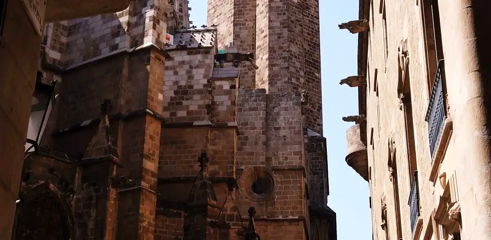 Looking up between Gothic stone walls and a tower against a pale sky, Barcelona (the stock page tags it Barcelona).