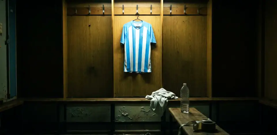 A pale blue and white striped shirt on a hook in an empty wood-panelled dressing room.