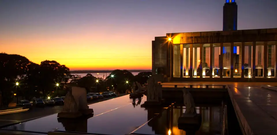 The Monumento a la Bandera, Rosario, at dawn, with its reflecting pool and an orange sky over the Parana.